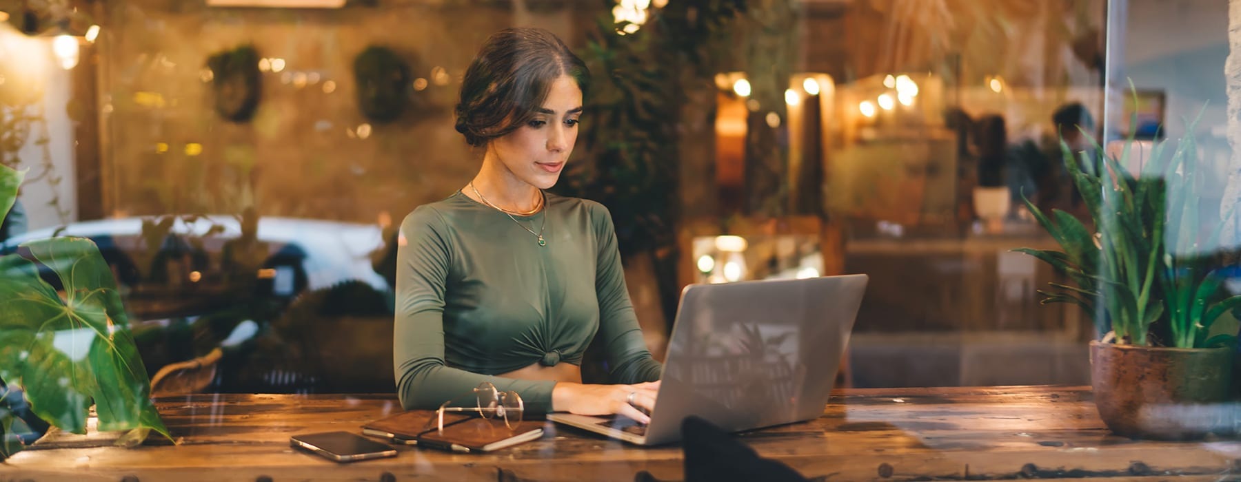 lifestyle image of a young woman sitting in a coffee shop and working on a laptop